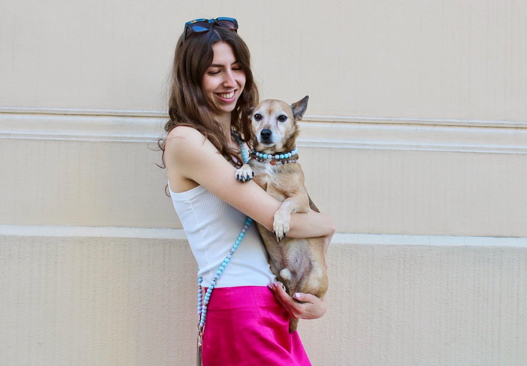 Frau mit hellblauer Handykette hält Hund auf dem Arm mit passendem hellblauen Halsband.